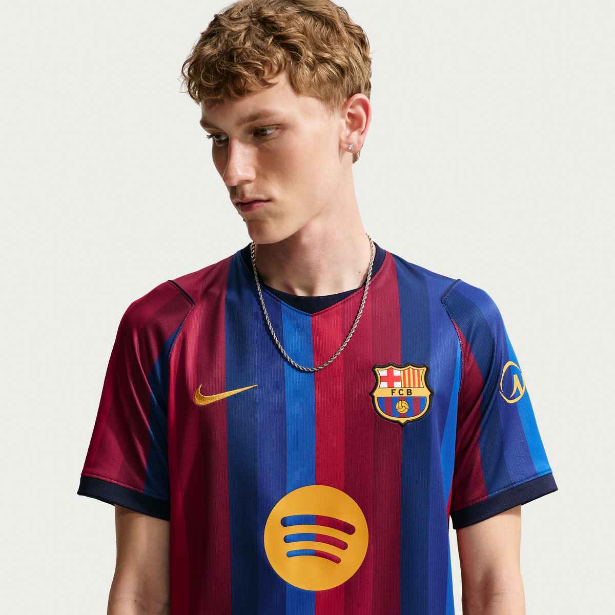 Person wearing a Barcelona soccer jersey with Nike and Spotify logos on a plain background