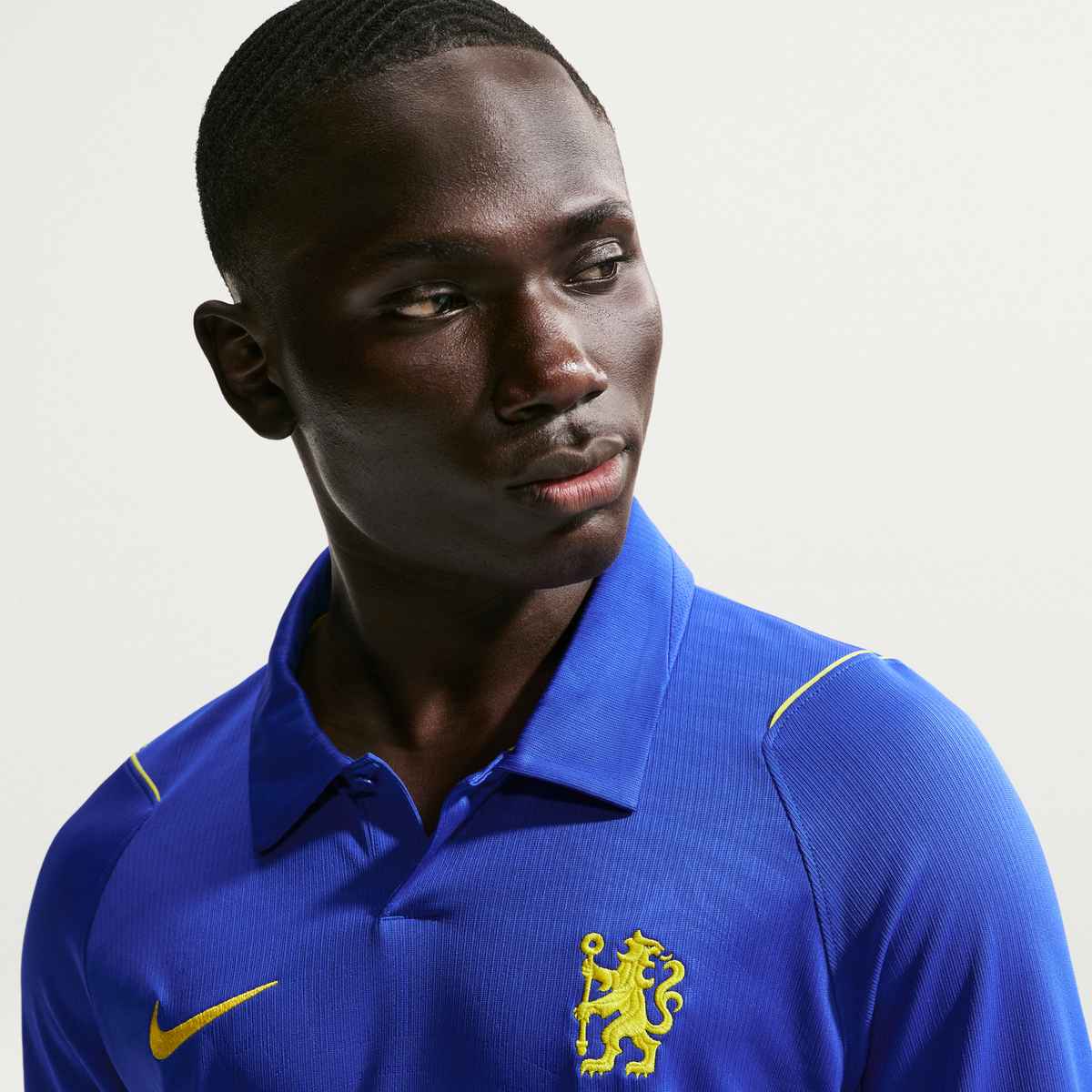 Person wearing a blue sports jersey with a yellow logo on a light gray background