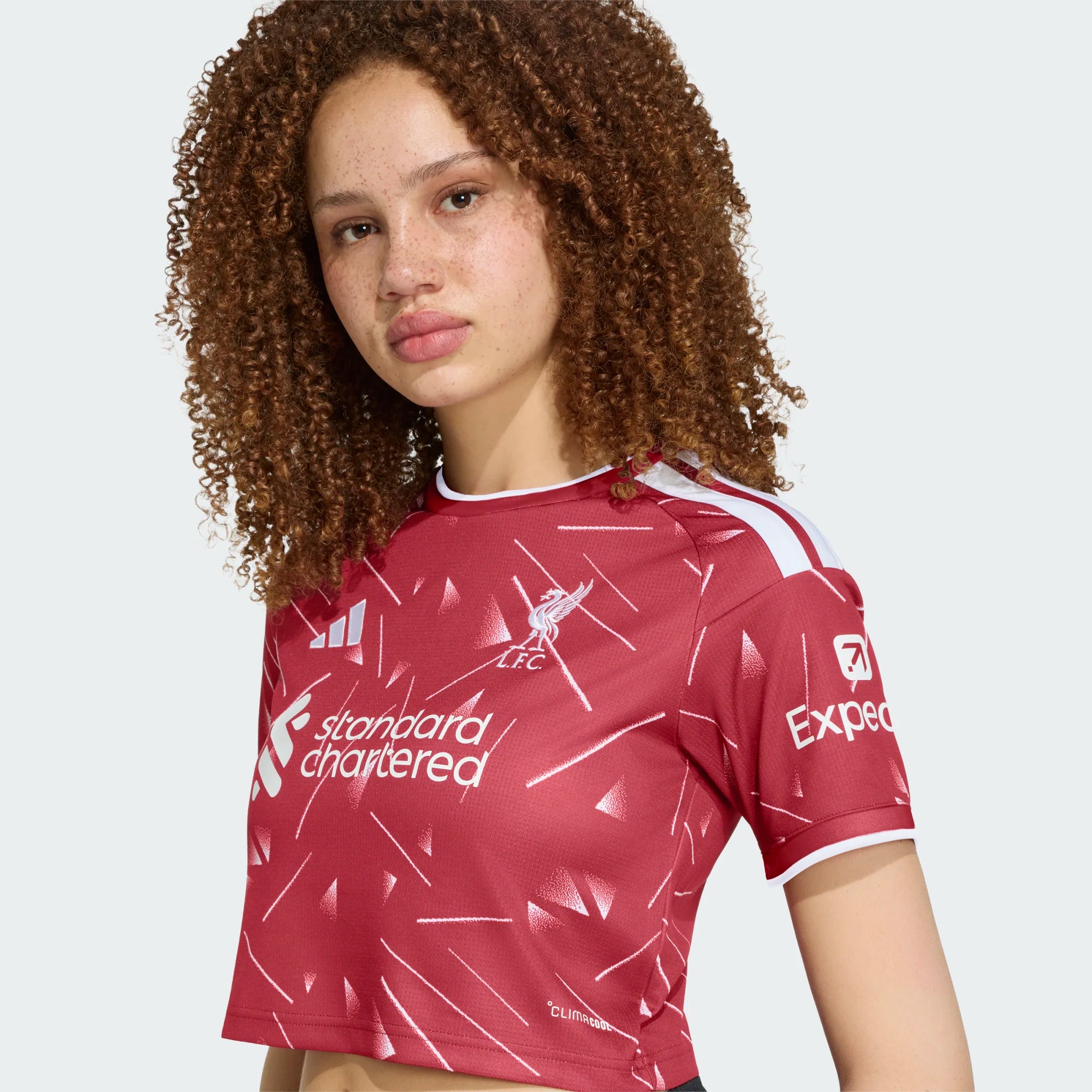 Person wearing a red sports jersey with various logos on a light gray background