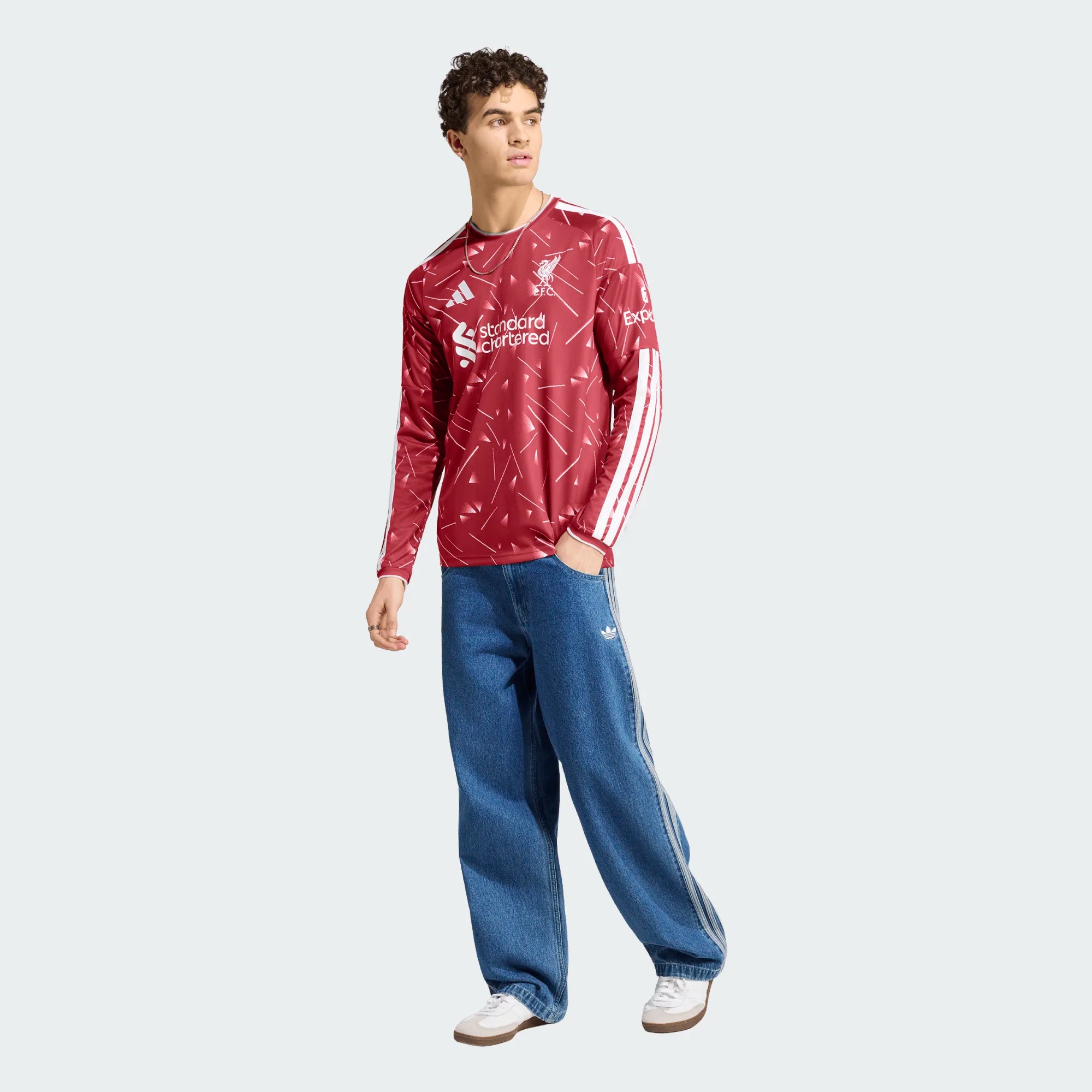Person wearing a red sports jersey with white patterns and blue pants on a white background